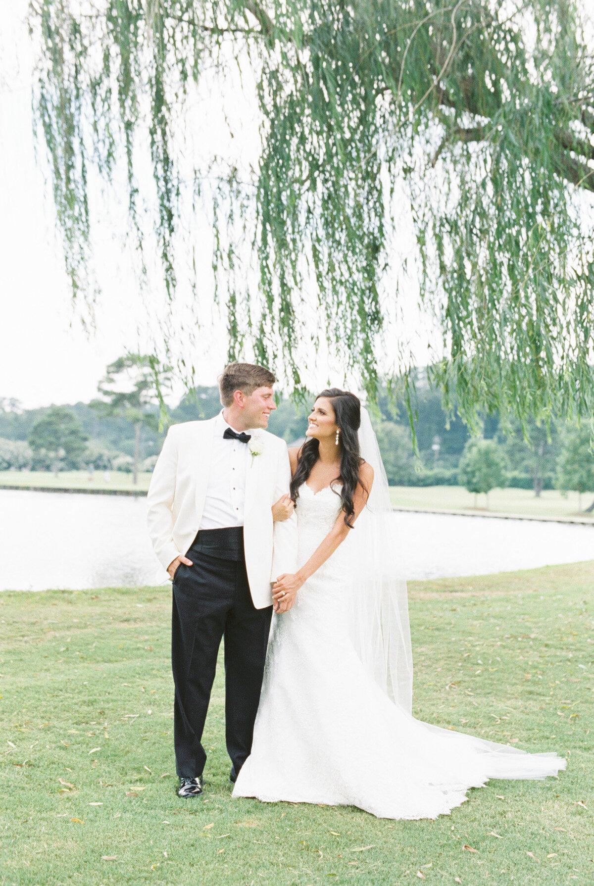 Bride and groom stand in classic black and white attire under a willow tree on a golf course by Birmingham wedding photographer, Kelsey Dawn Photography