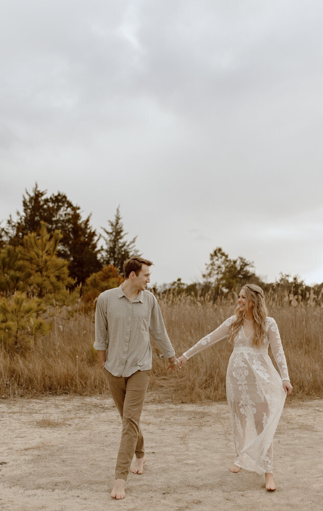 couple walks hand in hand through neutral colored location