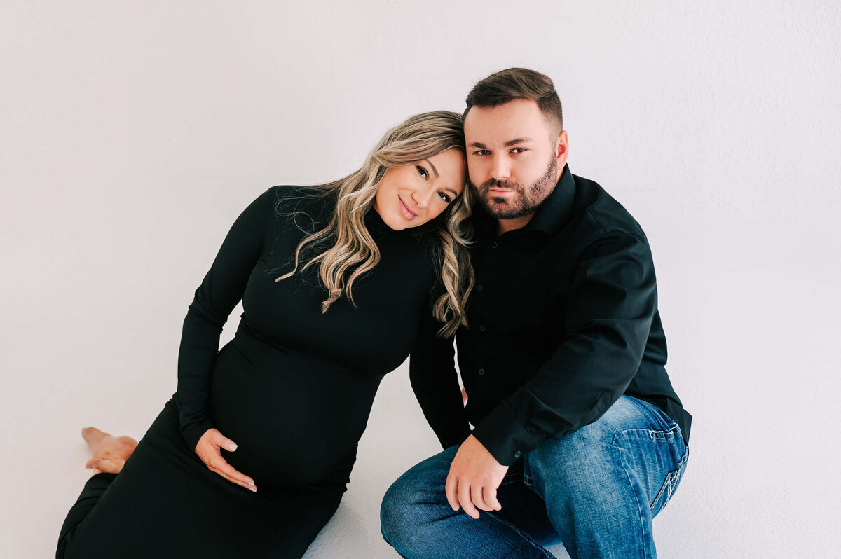 pregnanc couple sitting on floor cuddling during Branson MO maternity photography session