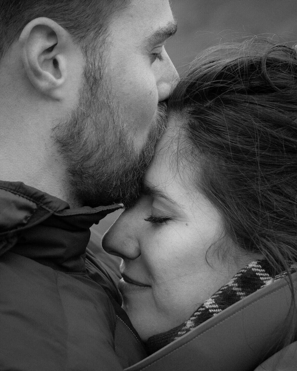 A newly engaged couple embrace as the man kisses the head of his fiancé