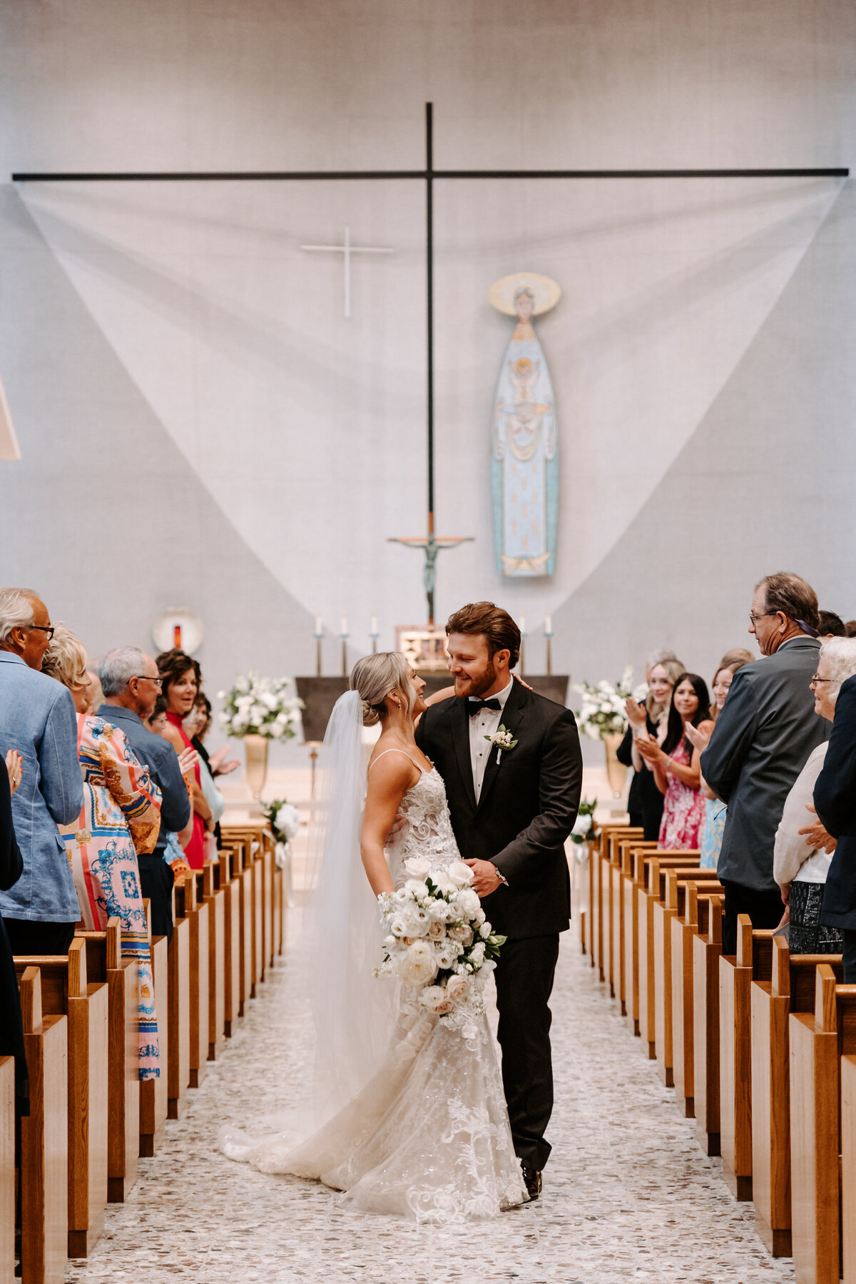 Newlyweds standing in the middle of an aisle with their guests standing on either side