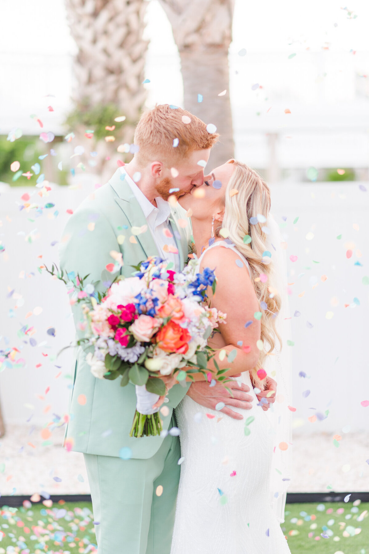 bride and groom kissing with confetti around them on wrigthsville beach, nc