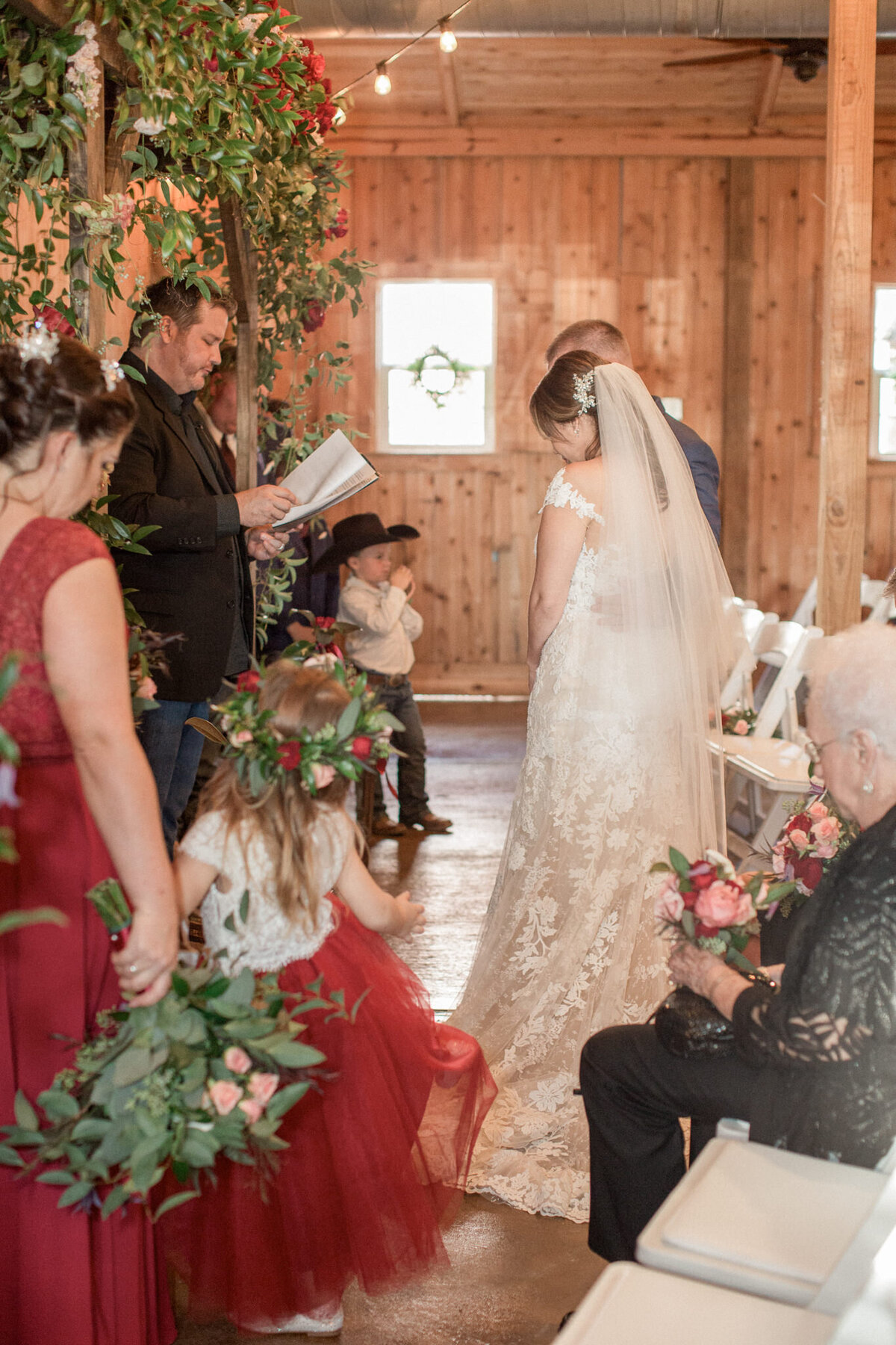 The bride and groom bow their heads  while their officiant prays