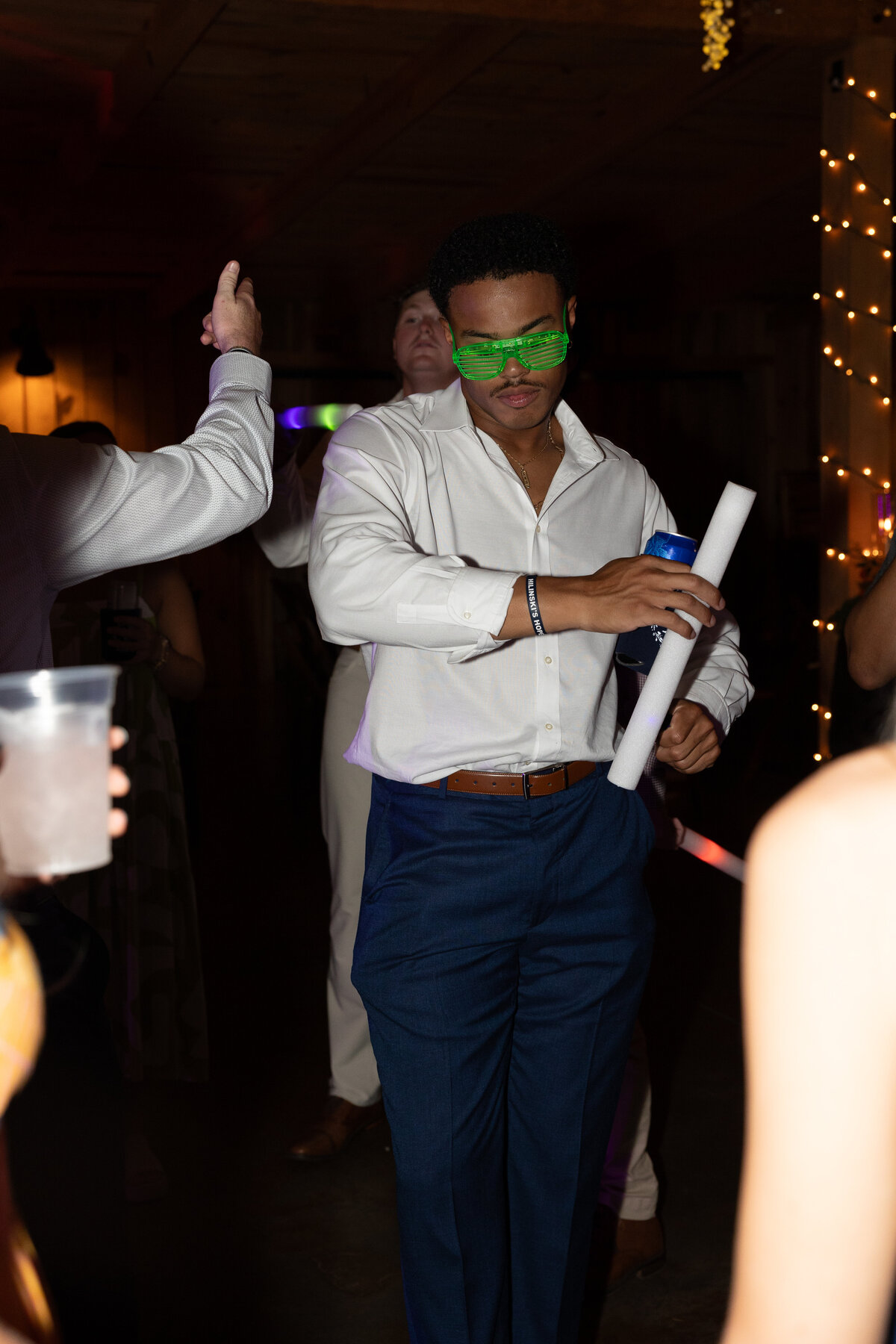 Guest dances at reception with sunglasses and glow stick
