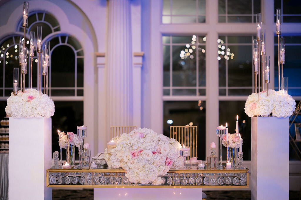 glass table with gold accents decorated with white floral arrangements