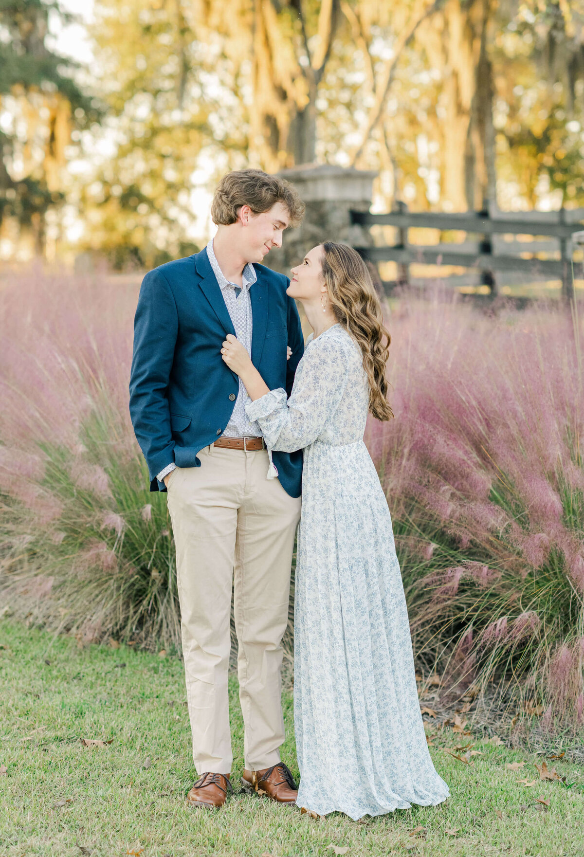 Engaged alabama couple standing in a field cuddled closely for engagement photos