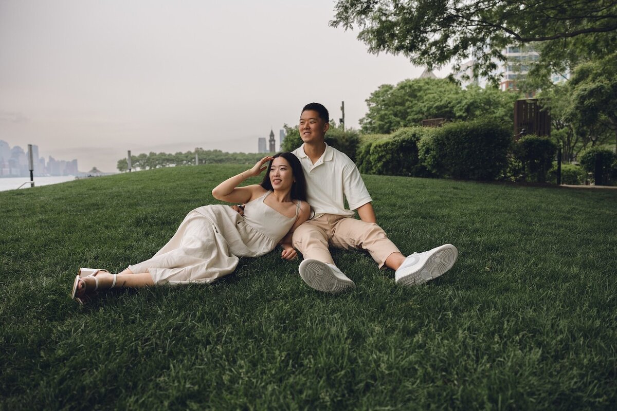 Couple relaxing on a grassy hill overlooking NYC skyline