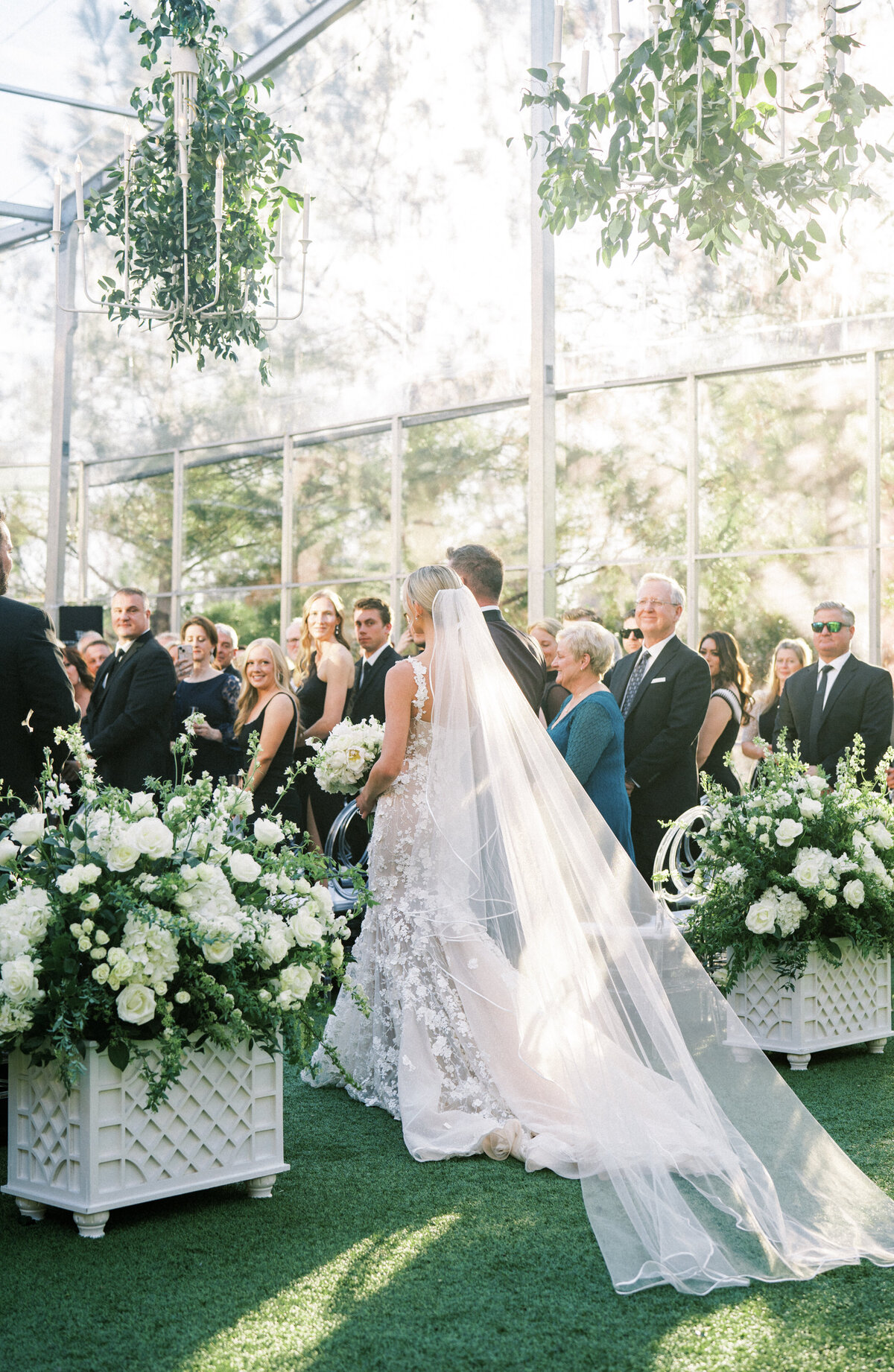 Bride walking down the aisle at Hotel Drover, in a tented ceremony with greenery hanging from the chandeliers