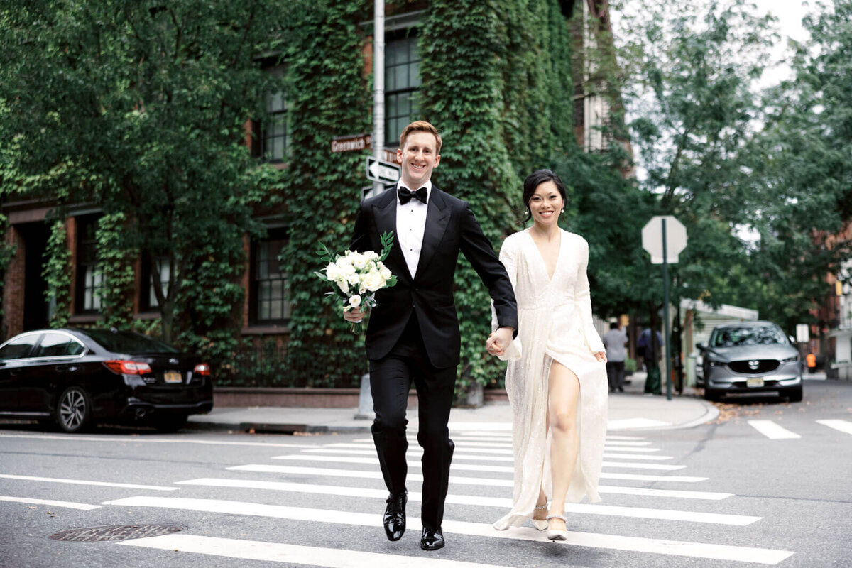The bride and the groom, who is holding the bouquet, are crossing the street at West Village, NYC. Image by Jenny Fu Studio