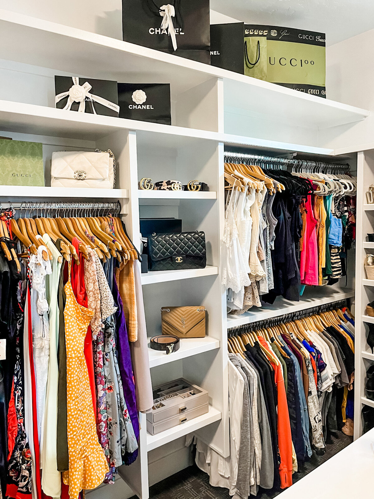 walk in closet organized with wooden hangers and purses on shelves