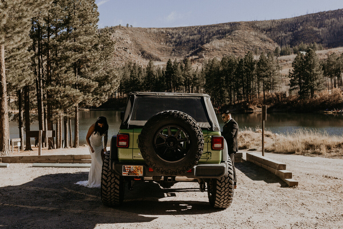 bride adn groom getting ready on either side of their jeep wrangler