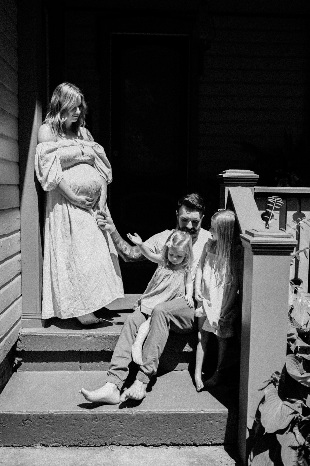 black and white image mothe rand father holding children on porch