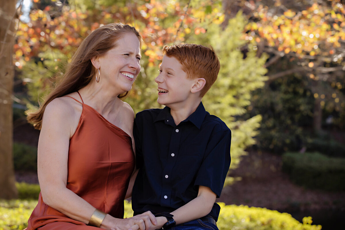 Proud mom with teenage son laughing together in autumn park setting at Ballantyne Corporate Park Charlotte NC