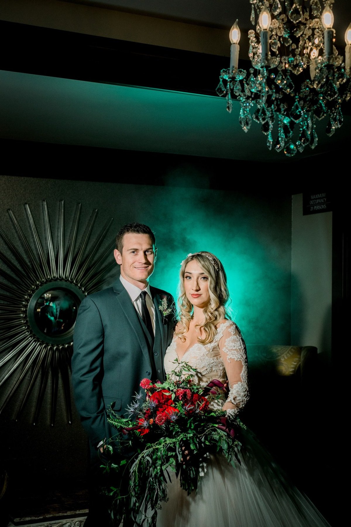 Bride and Groom pose together as she holds her large bouquet with a greenish mist behind them