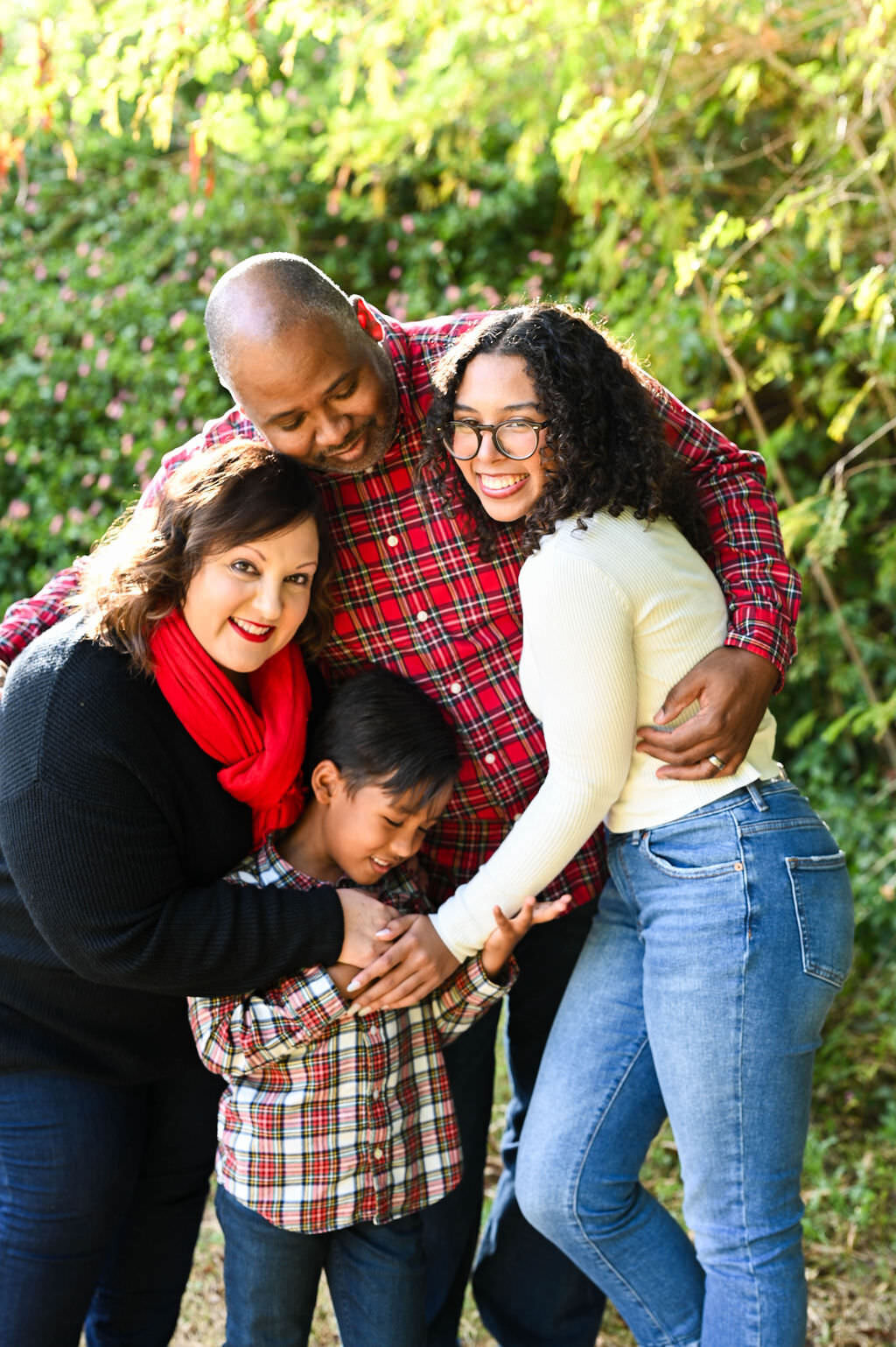 Parents and their two children all hugging together.