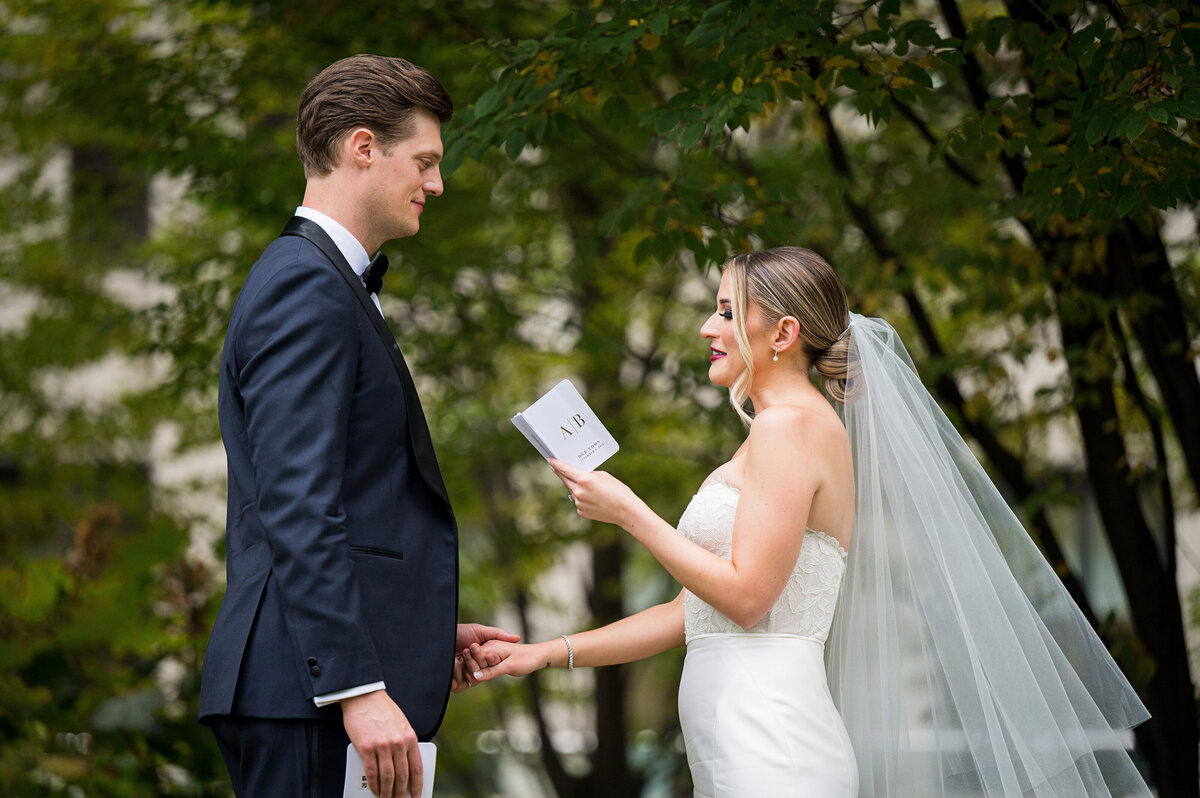 bride and groom reading vows to each other on wedding day