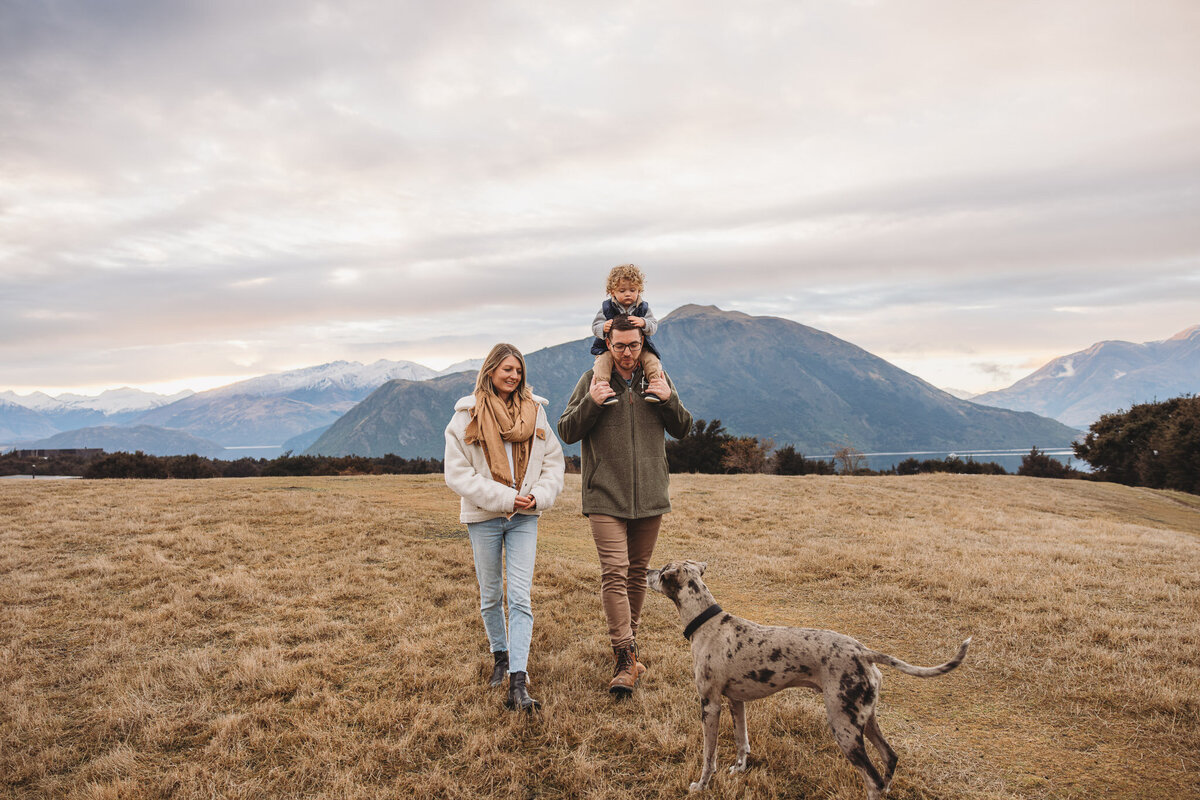 a family walking in the grass with their dog photographed by Captured by Bie during a family photography session in wanaka