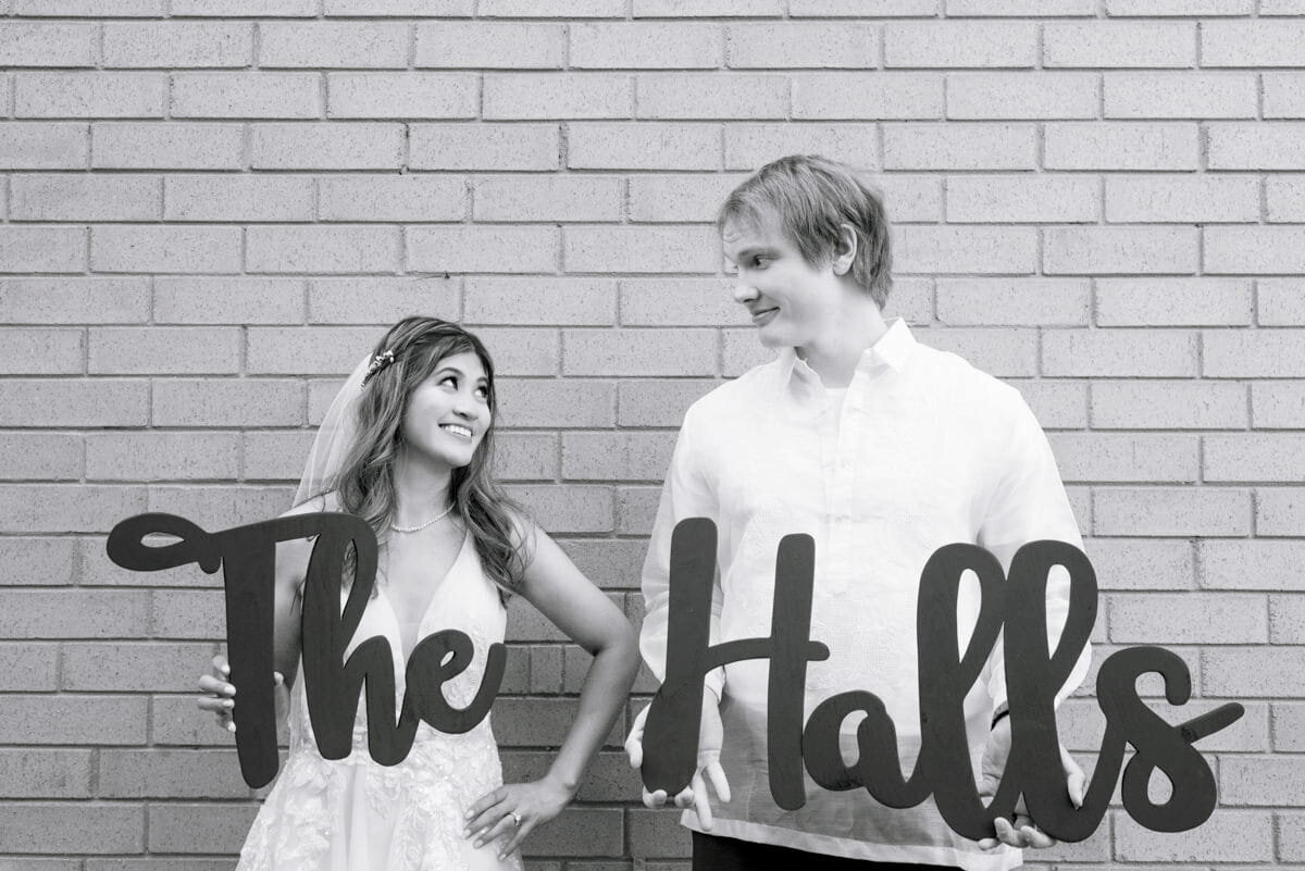 Wedding couple holding "The Halls" sign