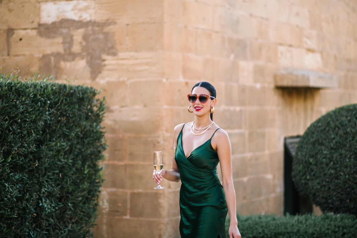 wedding guest outfit in emerald green satin dress at destination wedding