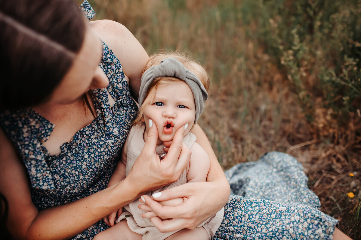 mom squishes baby's cheeks together during their longmont family photo session