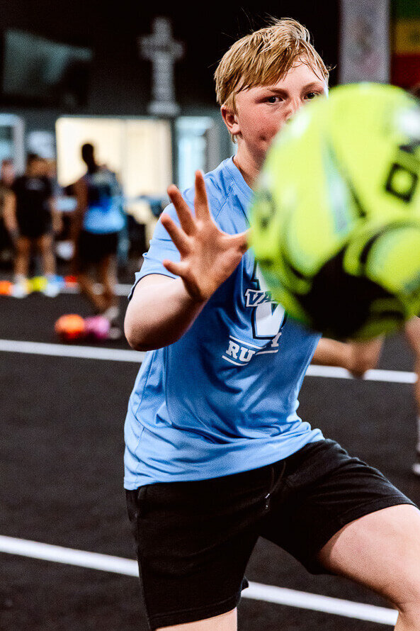 Boy catching rugby ball as a part of his training.