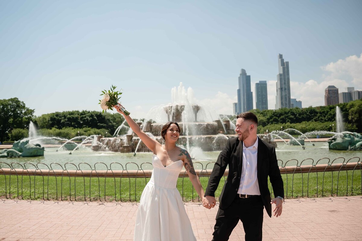 Bride and groom celebrate in front of Buckinghan Fountain in CHicago