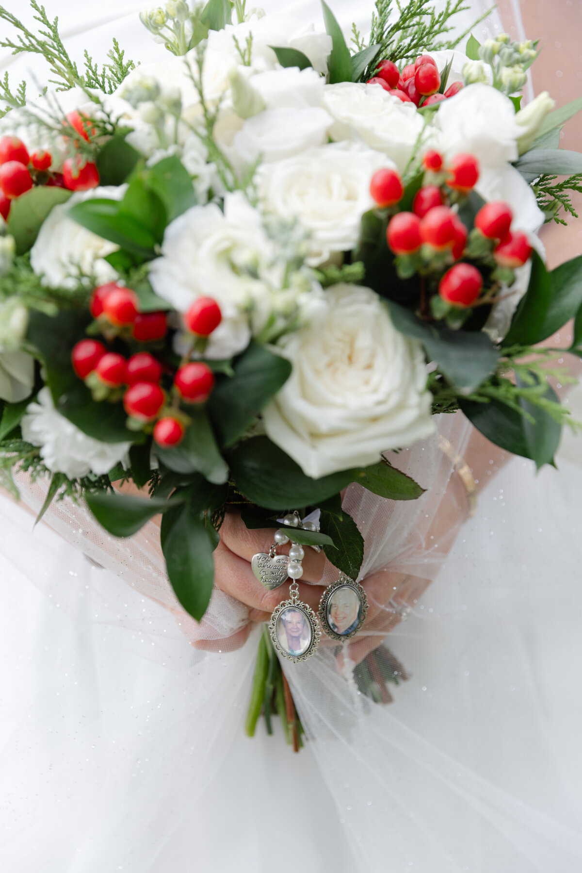 a wedding bouquet with red holly, white roses, and greenery