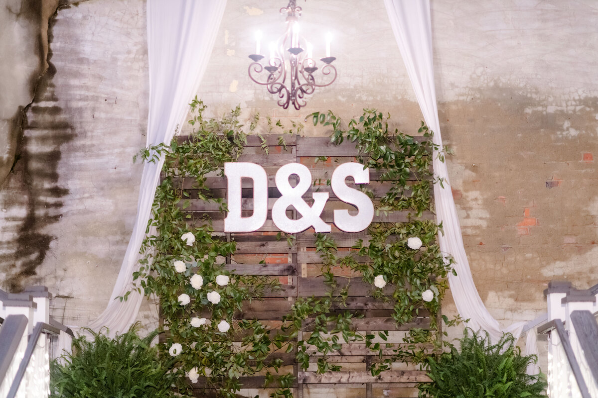rustic wedding decor of a wood palette wall with white roses and large white letters decorating the wood
