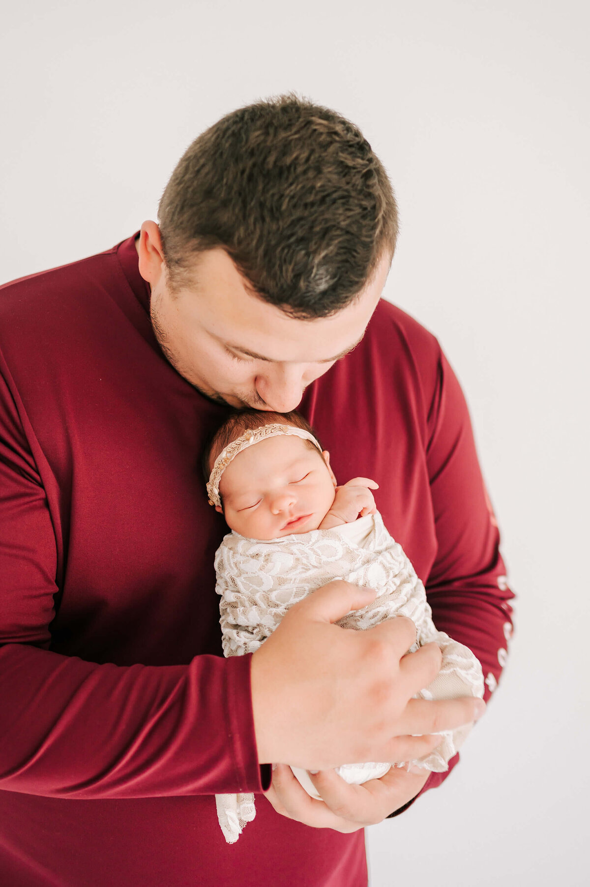 dad kissing newborn baby girl head during Springfield Mo newborn photography