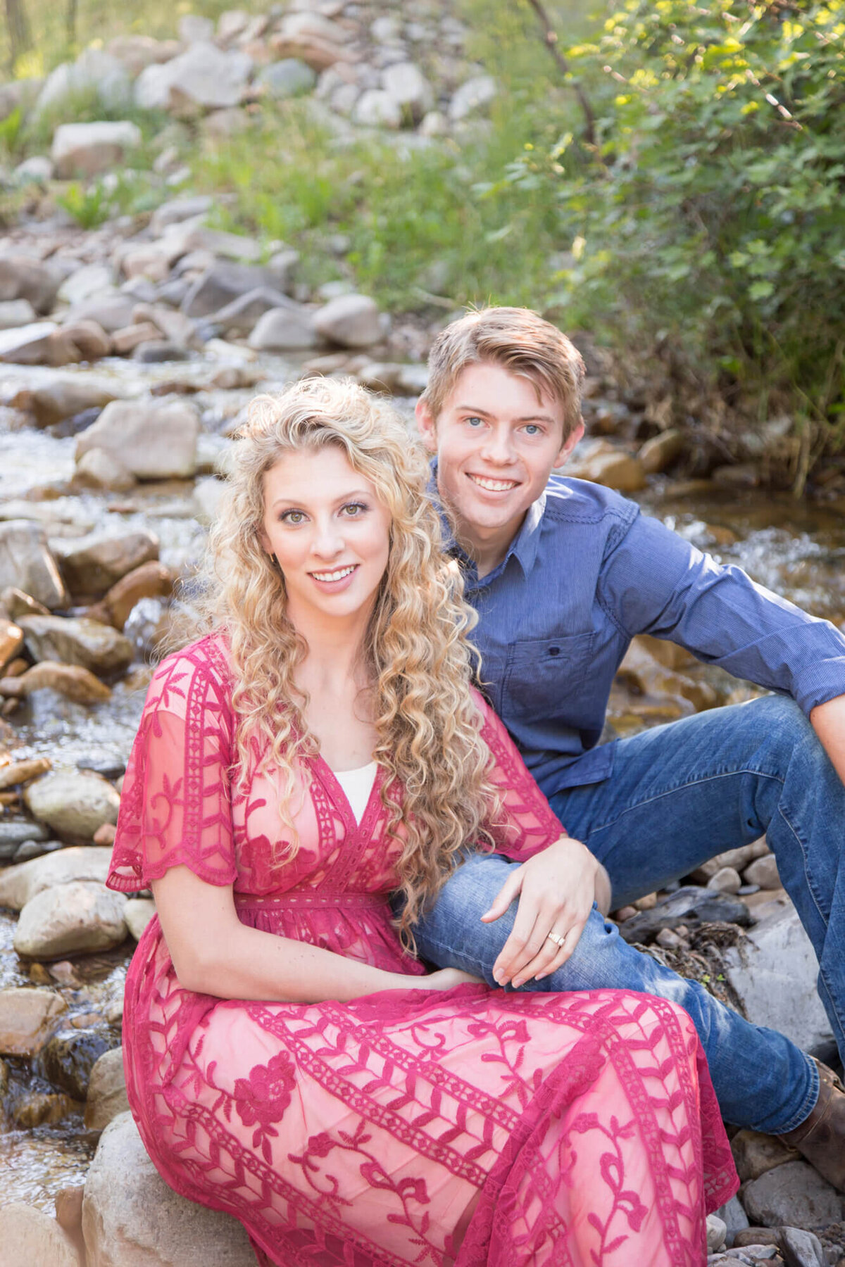 a  Las Vegas couple sitting on rocky riverbed to celebrate their engagement