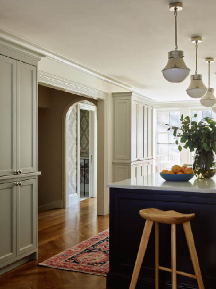 Brownstone Renovation Designers designed a traditional kitchen with light grey cabinets, a navy blue island, and a mid-century modern stool.