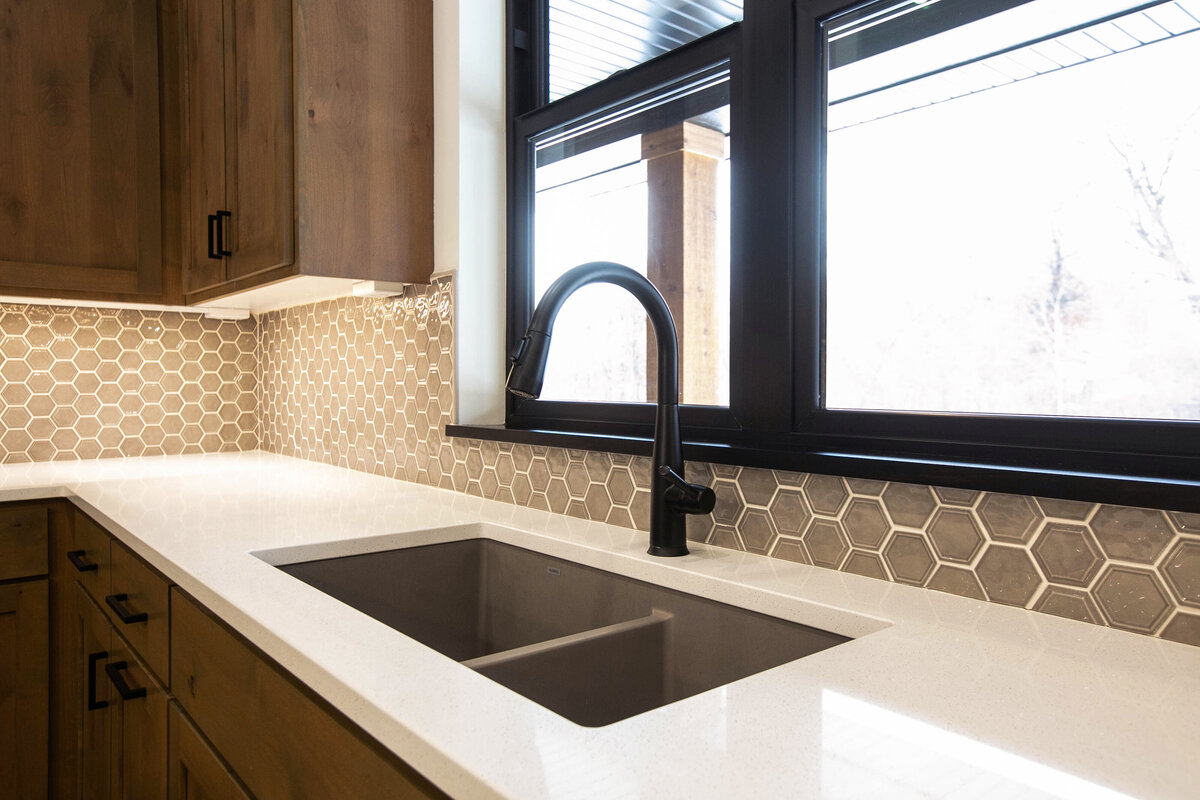 Open kitchen with dark cabinets, large island, and quartz countertops in an Elk River custom home
