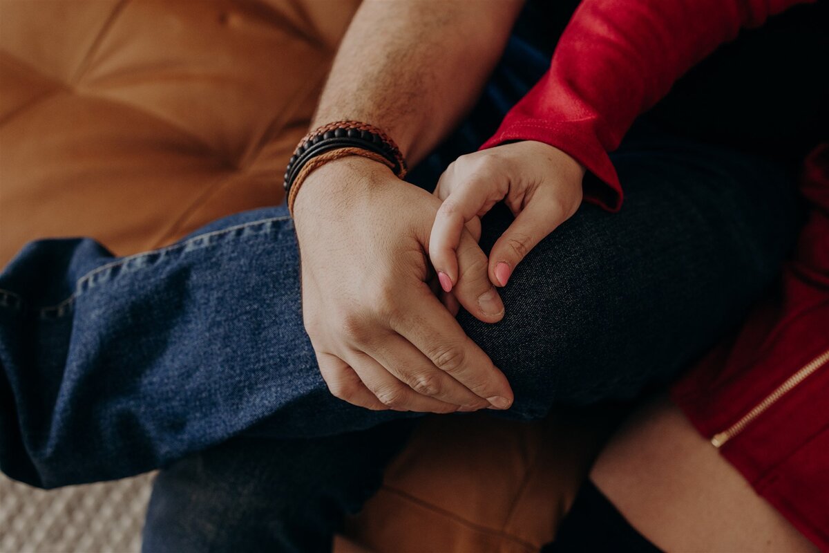 couple on a brown leather couch holding hands and looking into each other's eyes