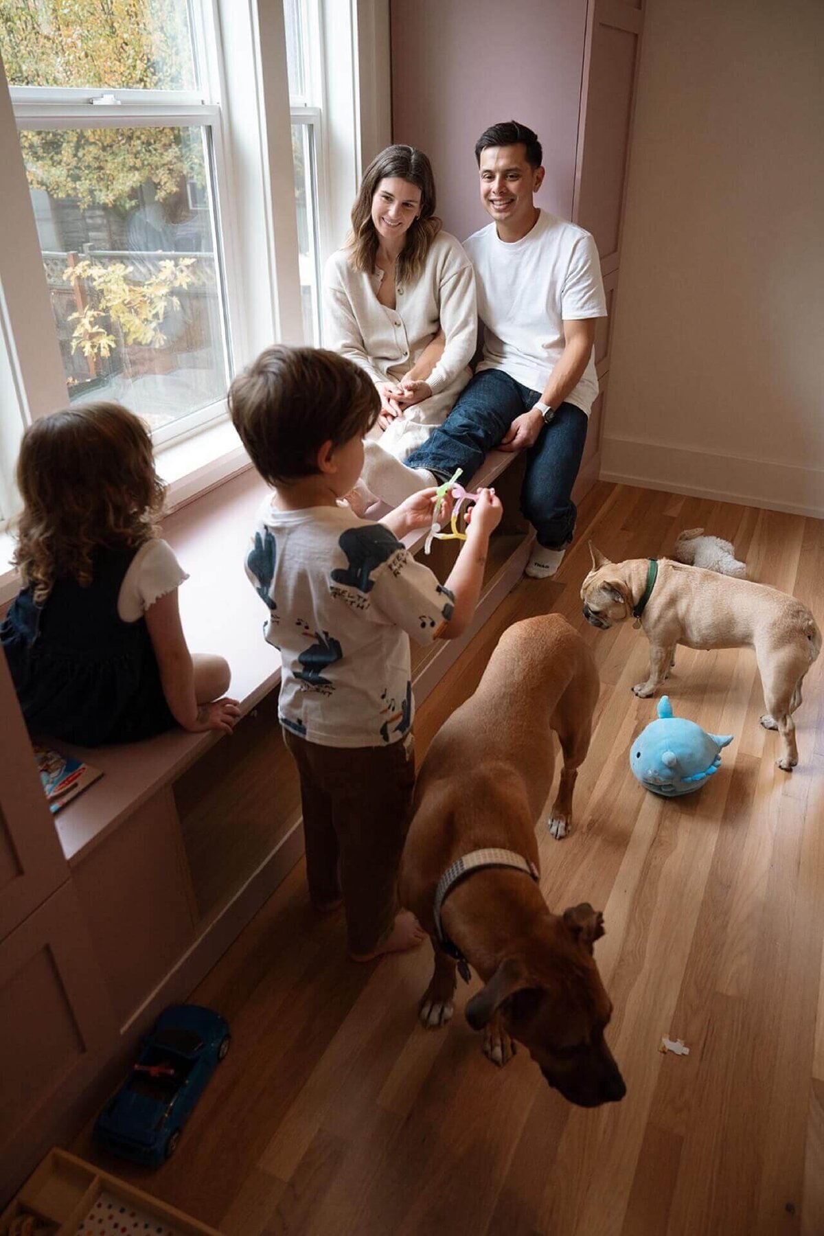 a candid photo of a family of four at home with their kids in their modern playroom