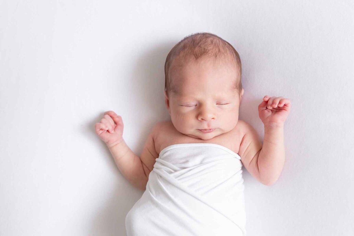 Puur en minimalistisch: een newborn fotoshoot waarbij de baby centraal staat op een witte achtergrond.