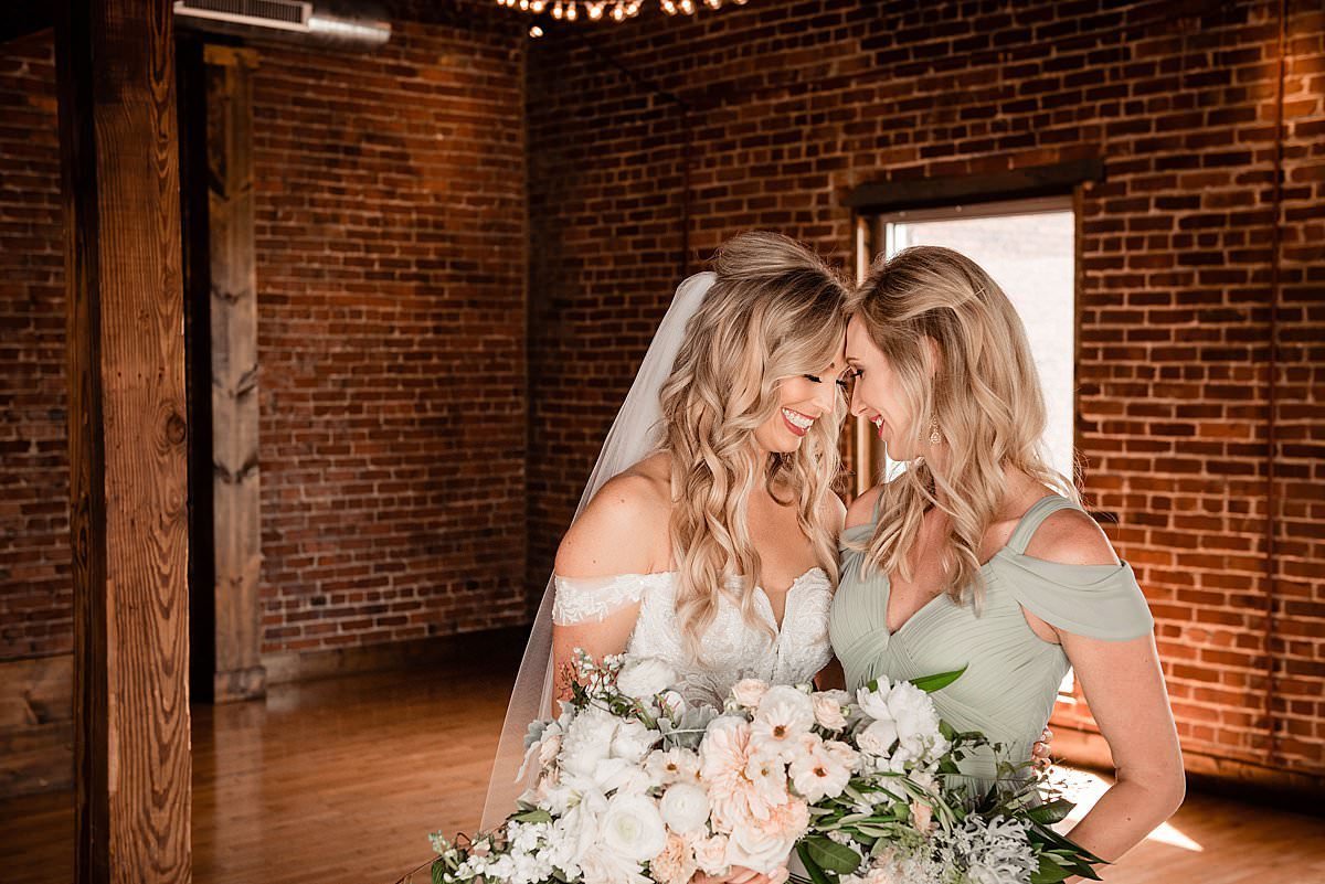 Bride touching foreheads  with her sister who is her maid of honor