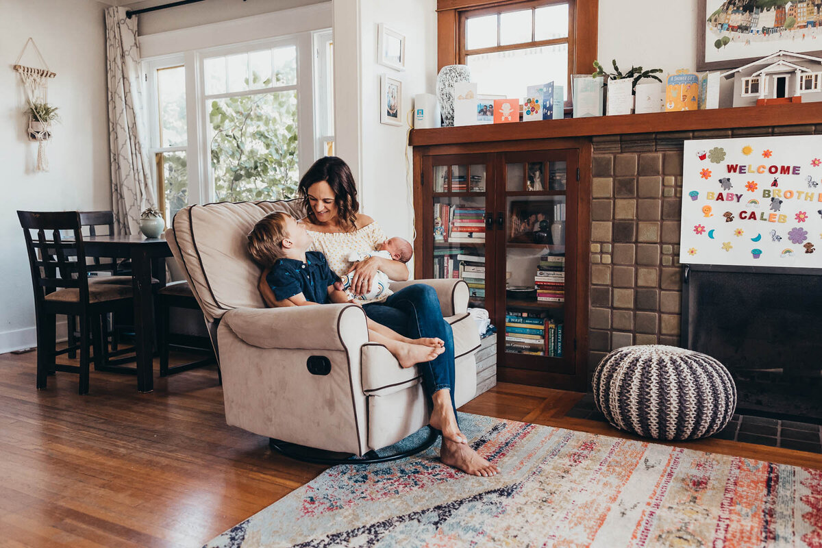 A mom sits in a chair in her San Diego living room with her two sons