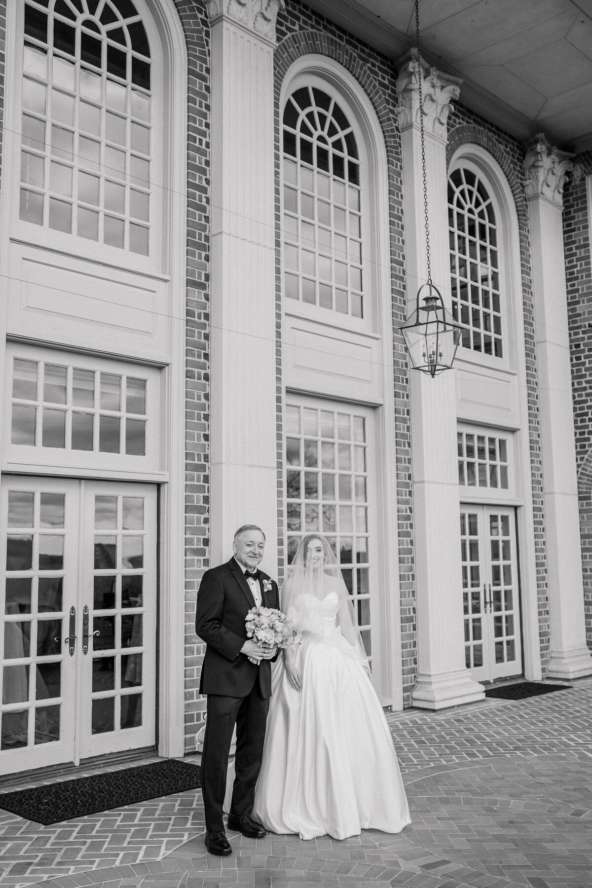 Father of the bride walking the bride down the aisle in black and white