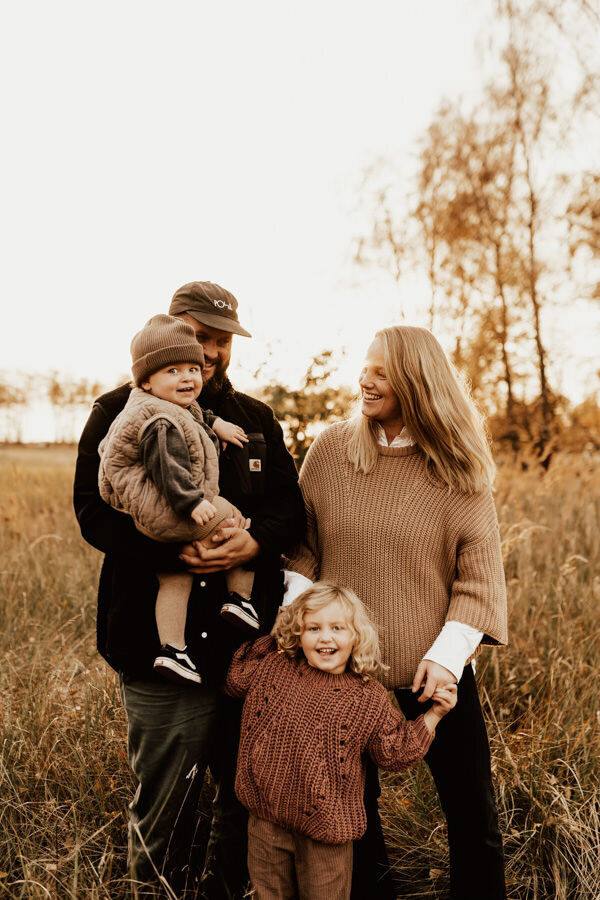 familj står i högt gräs med stickade kläder i solnedgången under familjefotografering i halsmtad