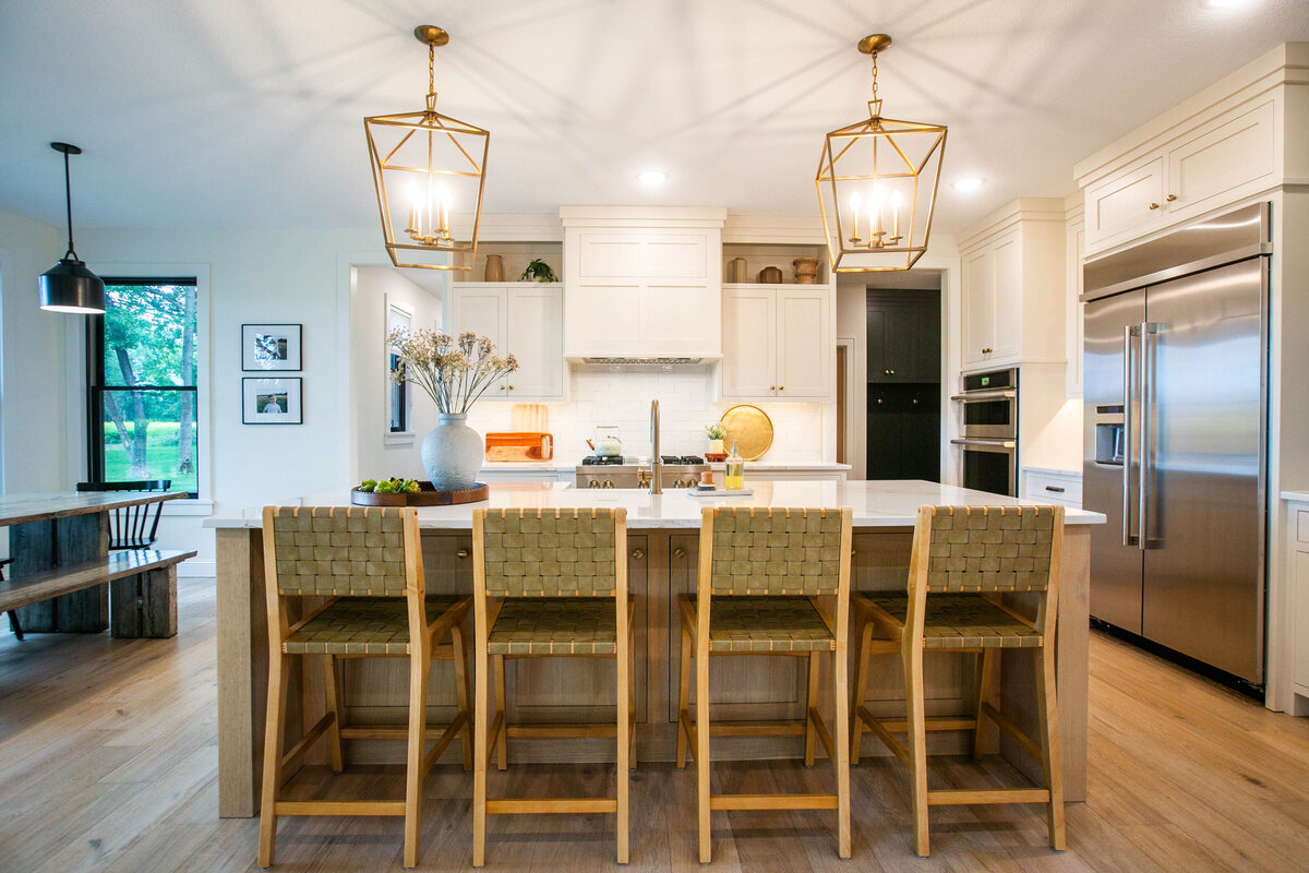 Open kitchen with white cabinets, large island, and quartz countertops in an Otsego custom home
