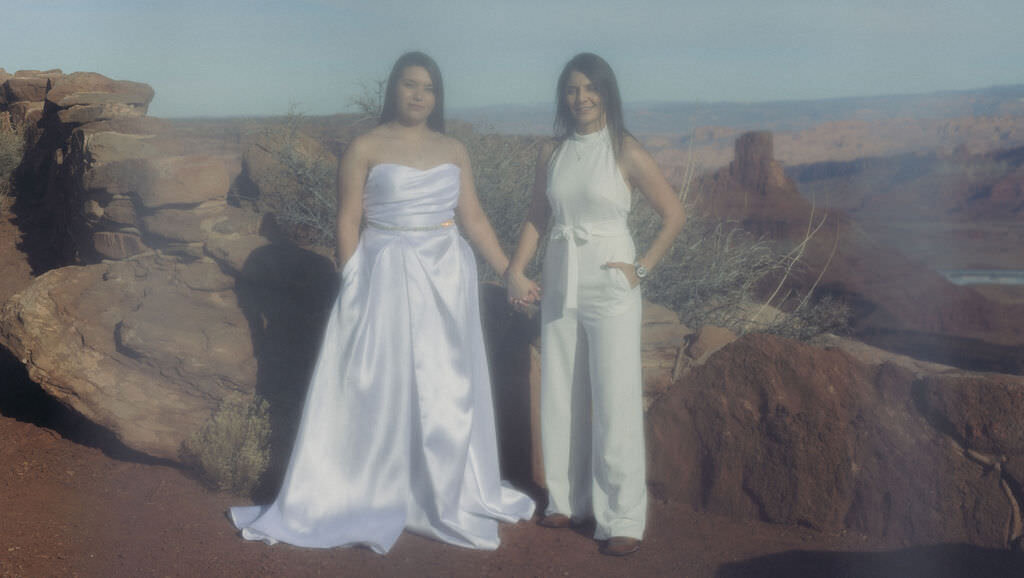 A wedding couple holding hands while on a canyon.