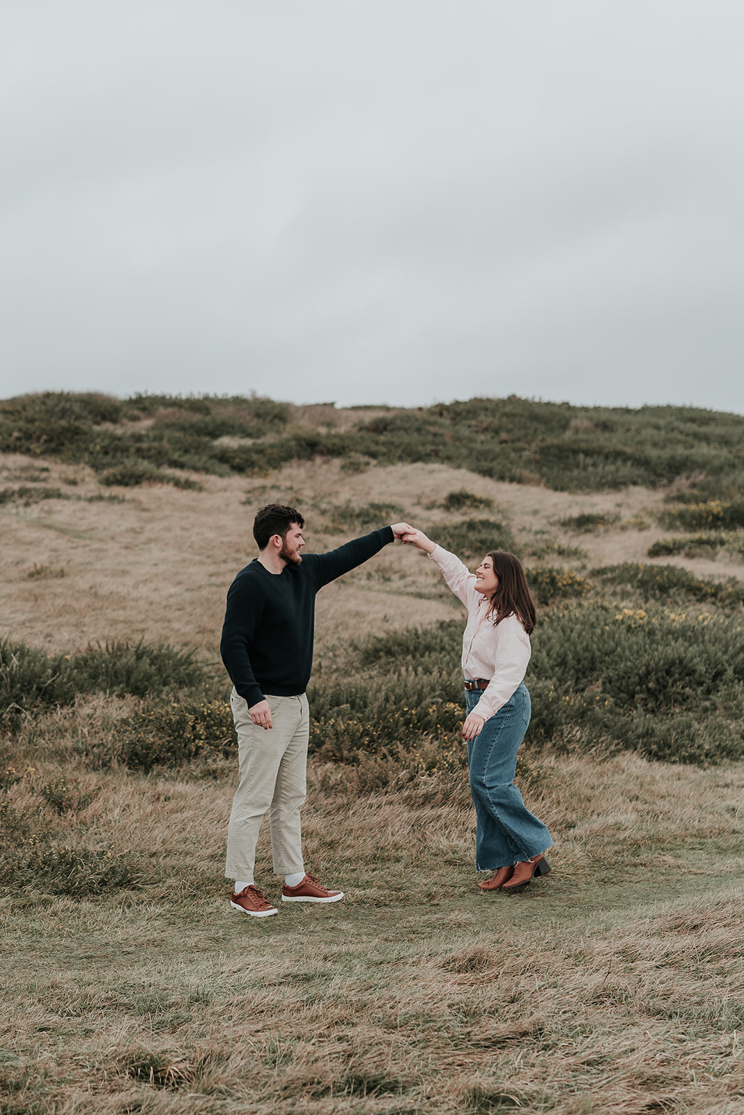 Man gently spins fiance round dancing up the downs on Beachy Head