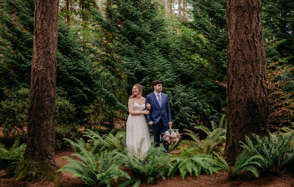Summer wedding at Evergreen Gardens in Ferndale, WA. Couple in wedding attire standing in a forest.
