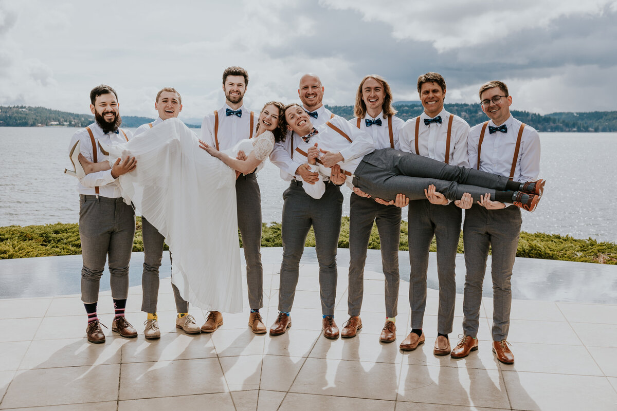 Groomsmen hold up bride and groom in front of lake Coeur d'Alene.
