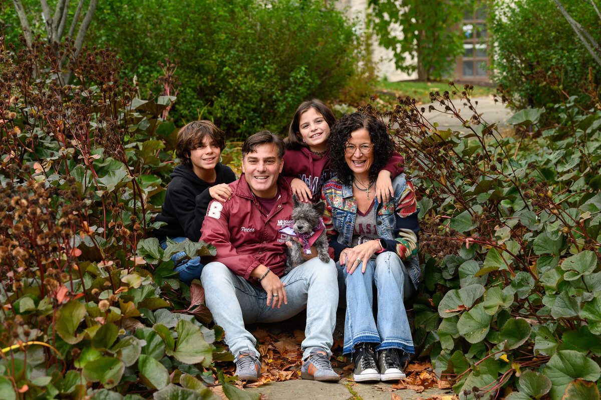 Mom and dad sitting on a step at McMaster University with their son and daughter and dog for their fall family photography session