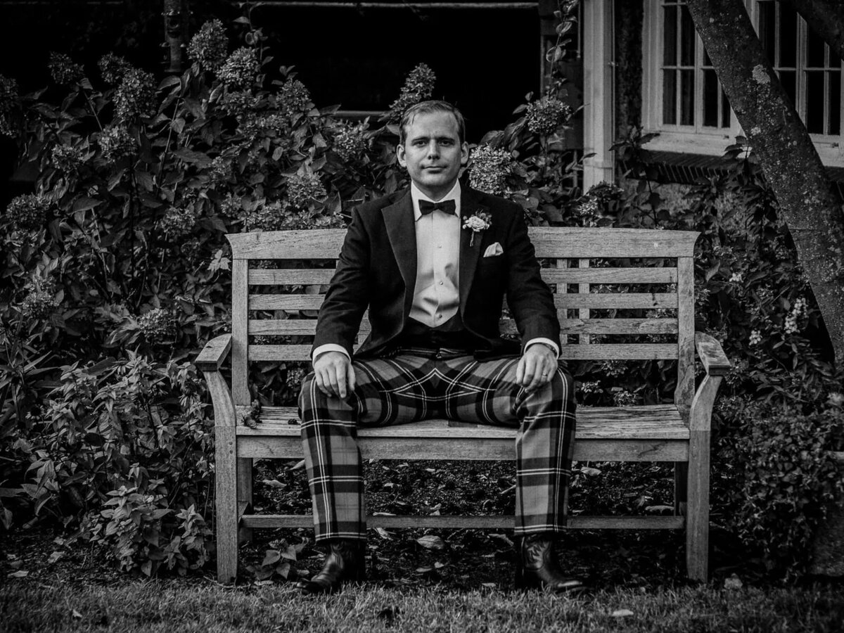 A man in plaid pants sitting on a bench.