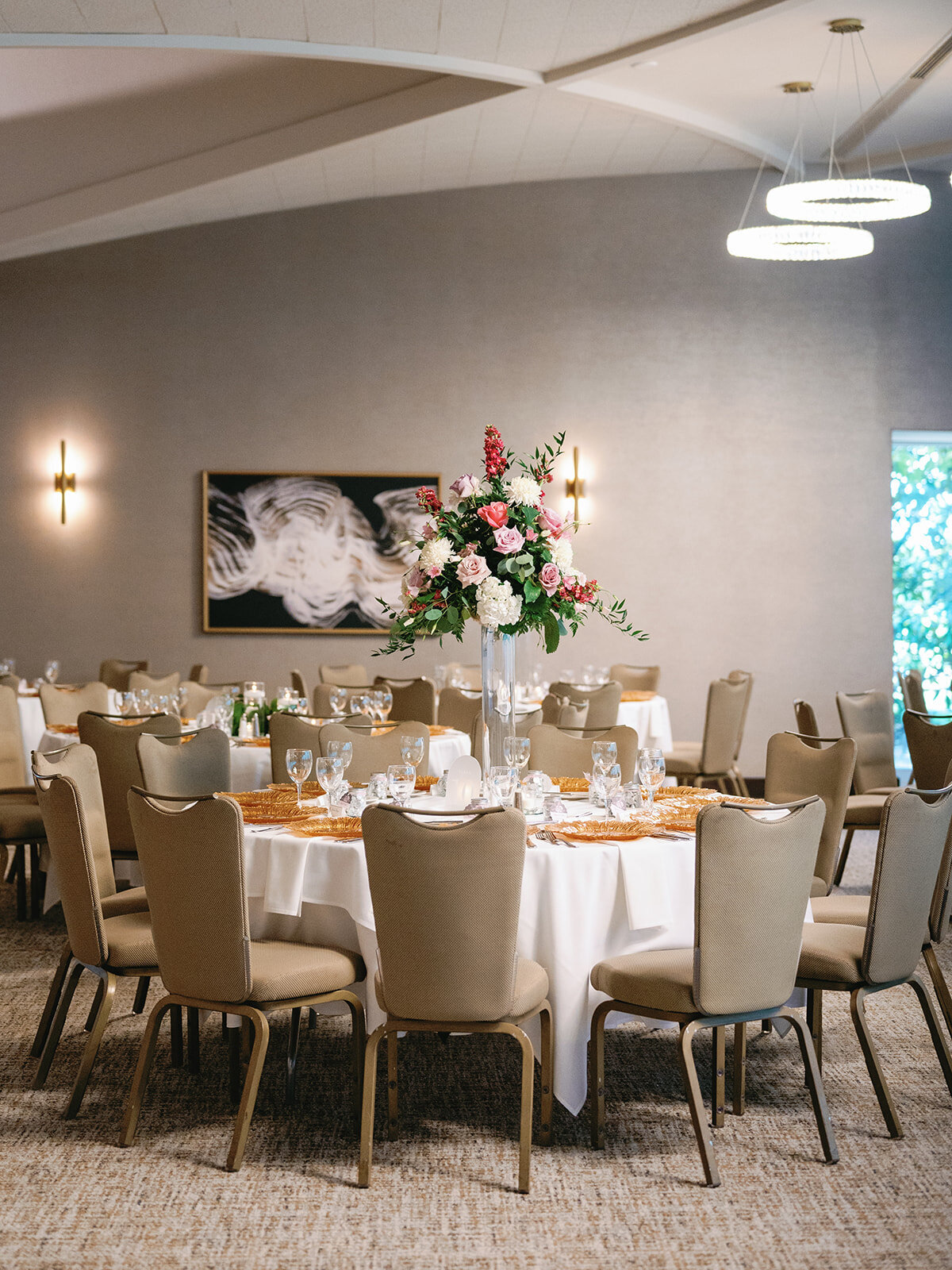Elegant reception tables featuring tall candle-lined centerpieces, delicate floral arrangements at Meadowbrook Country Club