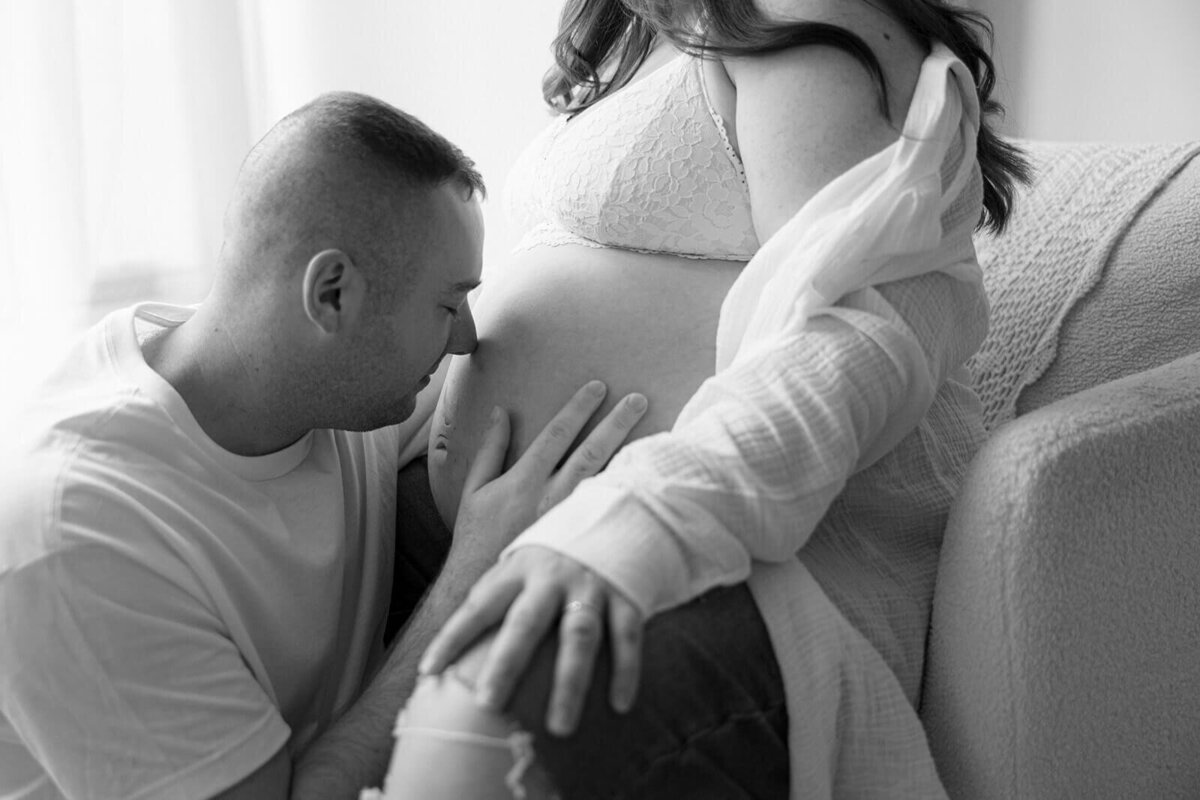 Man with face resting on baby bump at  Finger Lakes Maternity session