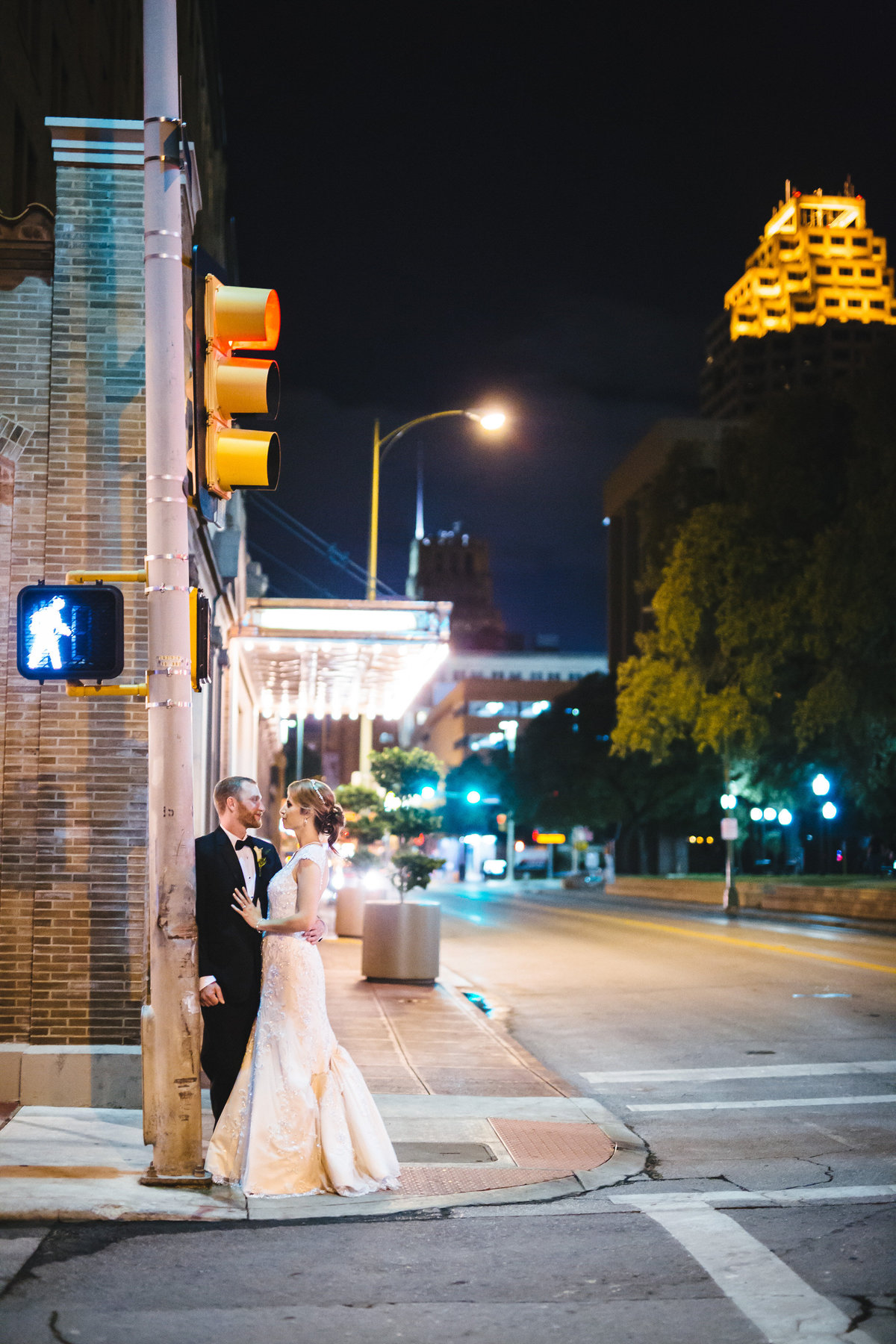 bride and broom posing under street light in front of the St. Anthony Hotel a Luxury Collection Hotel in San Antonio
