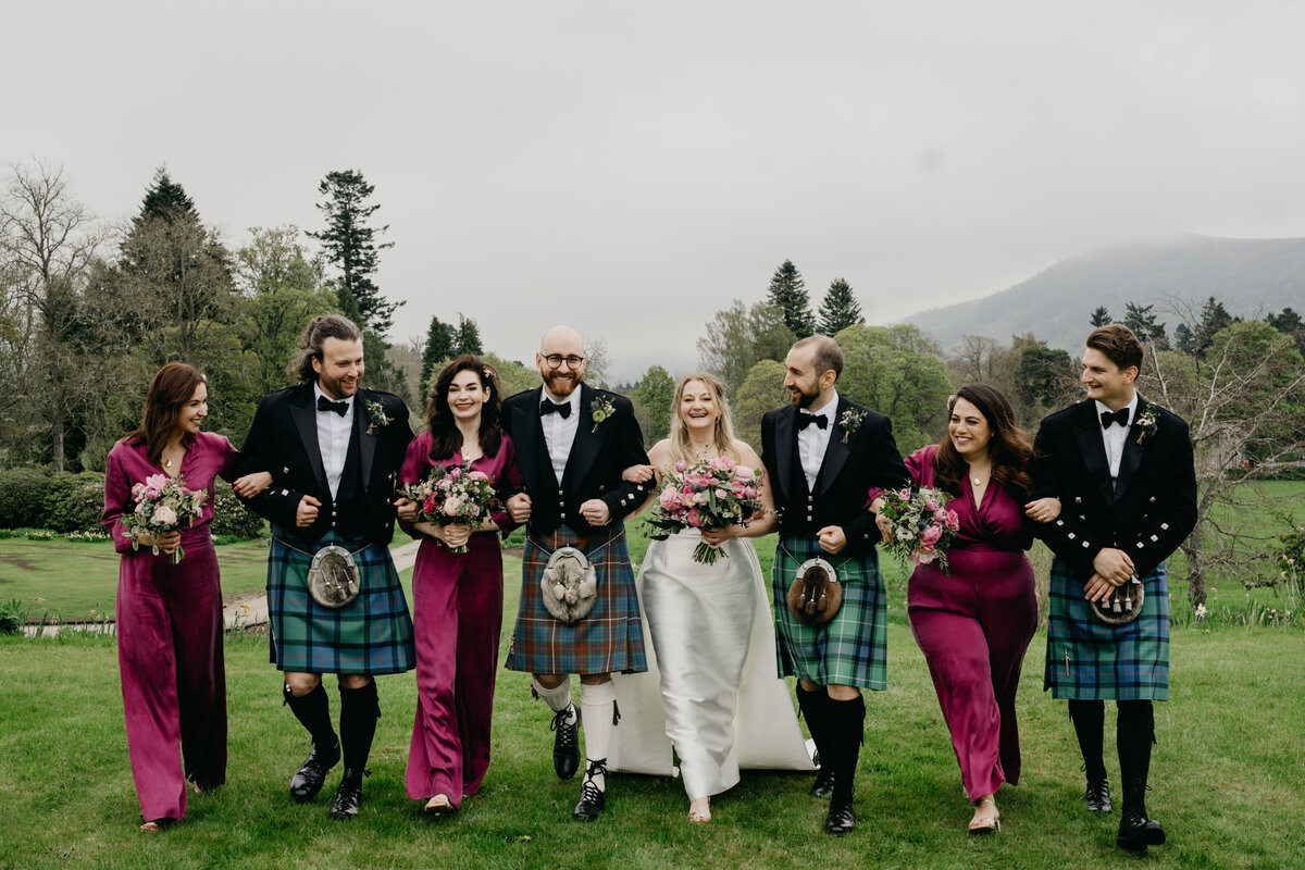 A wedding party walk candidly towards their photographer in the grounds of Blair Castle.